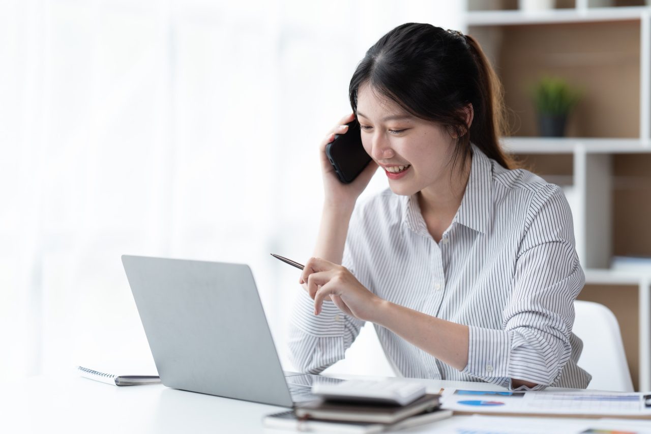 asian businesswoman in formal suit in office happy and cheerful during using smartphone and working