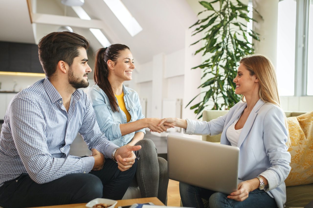 real estate businesswoman shaking hands during meeting with potential homeowning couple